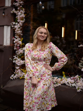 A blonde lady wears a silk floral dress